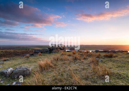 Bellissimo tramonto sulla roccia di granito a formazioni Tregarrick Tor Siblyback affacciato sul lago a Bodmin Moor in Cornovaglia Foto Stock