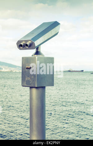 Pagato all'aperto telescopio turistica in acciaio inox sulla costa del mare Vintage foto stilizzata con il vecchio stile nei toni del verde filtro Foto Stock