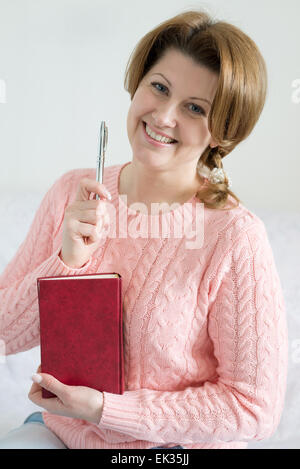 Donna positivo con un notebook e penna in una mano Foto Stock