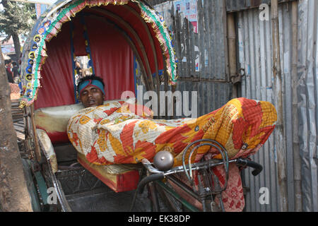 Un bangladese senzatetto prendendo un pisolino sul risciò a Tongi a Dhaka, nel Bangladesh. Foto Stock