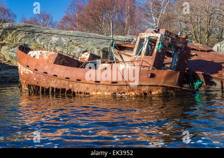 Retro e di lato di molto vecchio arrugginito naufragi vicino alla terra e rocce. Foto Stock