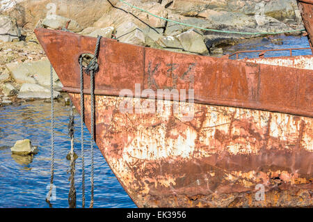 La ribalta di un vecchio arrugginito naufragio con corde appendere. Ancora in acqua ma vicino alle rocce. Foto Stock
