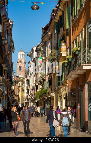 I turisti e gli amanti dello shopping lungo Via Giuseppe Mazzini con Torre dei Lamberti al di là, Verona, Veneto, Italia Foto Stock