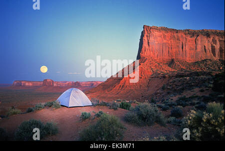 Una tenda per gli escursionisti sul bordo di una mesa affacciato sulla valle del monumento Indiano Navajo Tribal Park in Arizona e Utah con un Full Moon Rising sopra la valle. Foto Stock