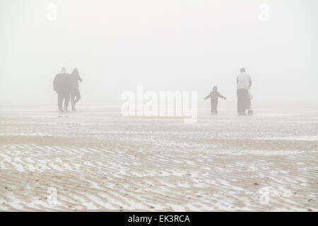 I vacanzieri di camminare sulla spiaggia in una fitta nebbia Foto Stock