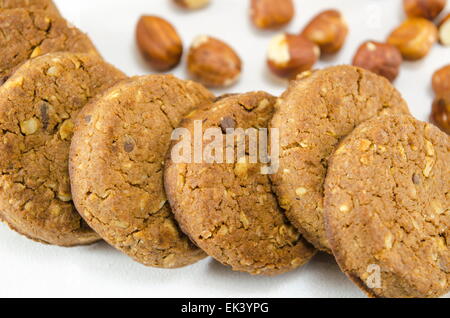 Biscotti integrali su sfondo bianco circondato con nocciole Foto Stock