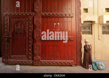 Omani boy e splendido cancello in souq, Nizwa, Oman Foto Stock