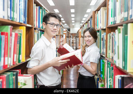 Coppia asiatica di studenti in uniforme in libreria Foto Stock