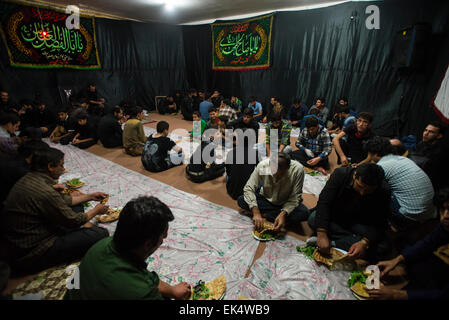 I partecipanti di Tazieh, teatro rituale del giorno di Ashura, mangiare beryun, Iraniano tradizionale piatto a base di agnello cotoletta e servita con nan-e-taftun pane, sulla cena dopo la prova di Ashura cerimonia in imam Hussein Shahr nel villaggio vicino a Isfahan, Iran Foto Stock