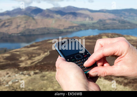 Concetto di immagine del telefono cellulare utilizzato per comporre 112 nelle montagne del Lake District Cumbria Regno Unito Foto Stock