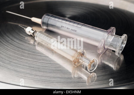 Due diverse siringhe di vetro e di plastica con tipi di aghi ipodermici sterili in acciaio inox lucidato vassoio medica Foto Stock