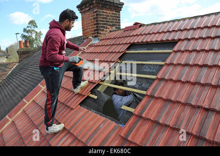 I costruttori si preparano a installare una finestra a tetto a spiovente del tetto rivestito di piastrelle nel sud di Londra Foto Stock
