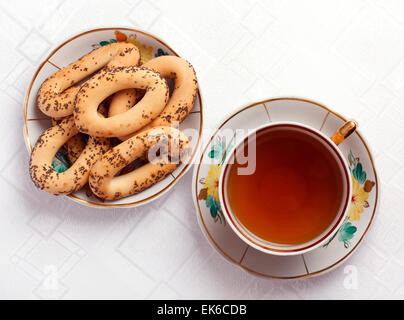 Bagel con semi di papavero e una tazza di tè sulla tovaglia Foto Stock