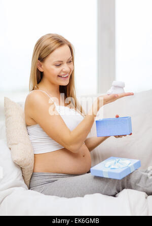 Sorridente donna incinta con confezione regalo e bootees Foto Stock