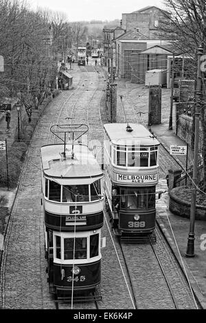 In bianco e nero - un driver sulla piattaforma del Tram 399 (Leeds 1926) come il tram 345 (Leeds 1921) passa sul suo modo al terminus Foto Stock