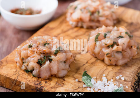 Il pollo crudo cotolette con erbe di olive Sfondo legno, fuoco selettivo Foto Stock