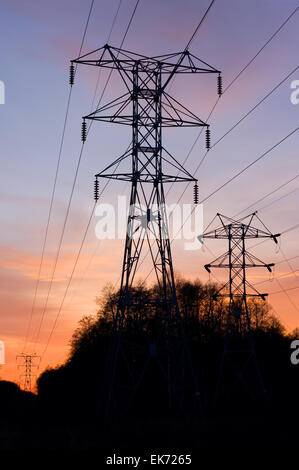 Silhouette di elettriche ad alta tensione della linea di alimentazione torri su un tramonto Foto Stock