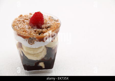Banoffee pie in un bicchiere rovesciato con caremel e panna montata Foto Stock
