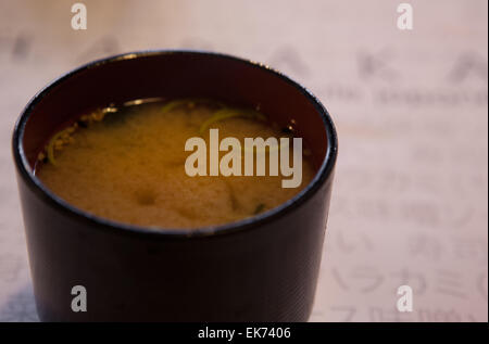 Un close-up di un nero e rosso ciotola con una deliziosa zuppa di miso Foto Stock