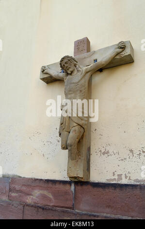 Danneggiata la statua di Gesù sulla croce senza gambe in corrispondenza di una parete della chiesa nell'Alsazia, Francia Foto Stock