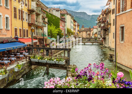 Un paesaggio panoramico immagine della bella e pittoresca Annecy città vecchia con fuori del ristorante posti a sedere affacciati sul Quai Annecy, Francia Foto Stock