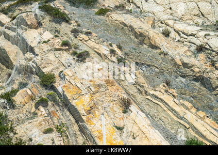 Le cadute di massi di protezione rete esagonale con rete a maglia su altamente stratificate, snodato e rotto rock mass. Foto Stock