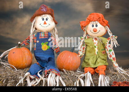 Autunno scarecrows con zucche in balle di fieno con il cielo al tramonto. Foto Stock