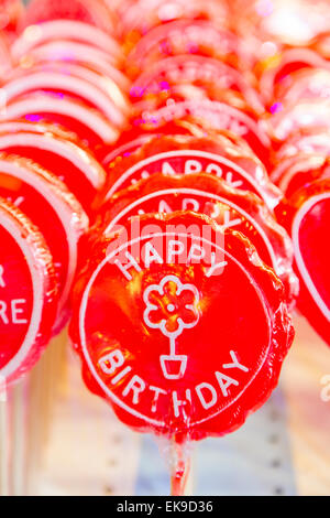 Una immagine di una fila di buon compleanno lollipop su bastoni in rosso brillante Foto Stock