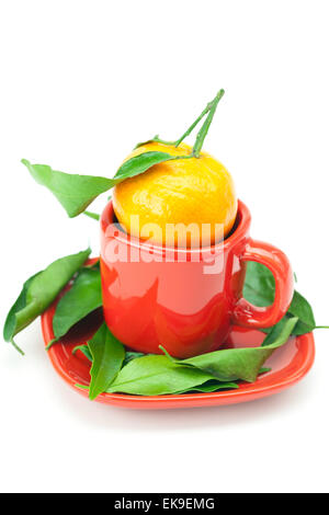 Il mandarino con il verde delle foglie in una tazza isolata su bianco Foto Stock