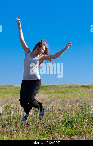 Giovane bella donna che si tuffa in campo contro il cielo Foto Stock