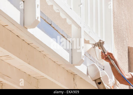 Pittore di casa indossando la protezione del viso verniciatura a spruzzo di un ponte di una casa. Foto Stock