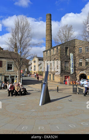 I turisti relax dall'ago Fustian scultura in St George Square, Hebden Bridge, West Yorkshire, Inghilterra, Regno Unito. Foto Stock