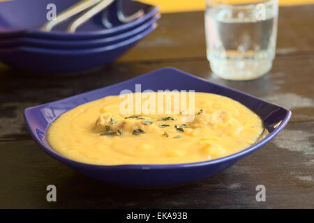 Giallo spesso dividere la zuppa di piselli con pollo e alcuni origano in foglie e servite in zuppa blu piastra (messa a fuoco selettiva) Foto Stock