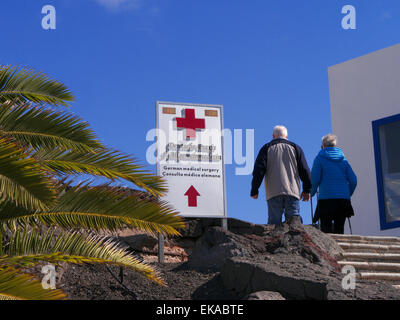 Trattamento medico in caso di malattia all'estero coppia di anziani e di firmare per il privato locale ambulatorio medico cura in Isole Canarie Spagna UE con blue sky & palme Foto Stock