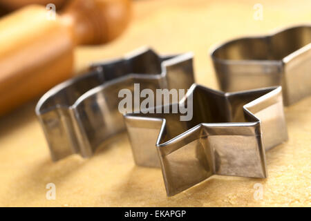 Natale cookie cutter e perno di rotolamento sulla pasta (messa a fuoco selettiva, focus sui due bordi anteriore del coltello a stella) Foto Stock