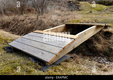 Costruzione di una piccola curva in legno ponte sul fosso Foto Stock