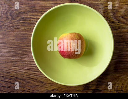 Red apple con gocce di acqua su una piastra verde. Vista superiore Foto Stock