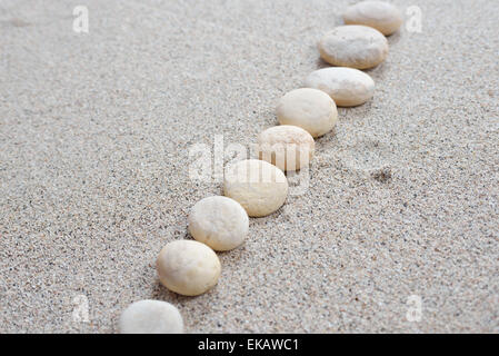 Alcune pietre disposte sulla spiaggia di sabbia con uno sfondo luminoso Foto Stock