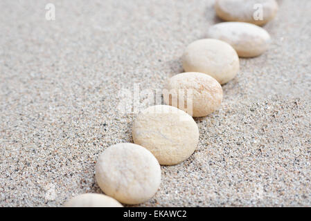 Alcune pietre disposte sulla spiaggia di sabbia con uno sfondo luminoso Foto Stock