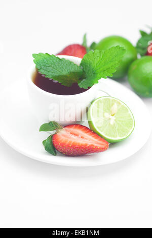 Tazza di tè, fragole, menta e lime isolato su bianco Foto Stock