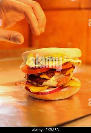 Hamburger in un panino con il formaggio e la pancetta nel caldo area di servizio di take away fast food Foto Stock