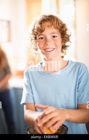 Ragazzo adolescente a spremere il succo arancia in cucina Foto Stock