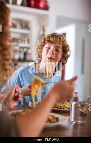 Ragazzo adolescente mangiare spaghetti al tavolo da pranzo Foto Stock