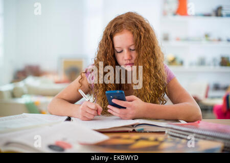 Ragazza adolescente scrivere note e utilizza lo smartphone Foto Stock