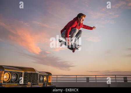 Ritratto di giovane uomo su skateboard a metà in aria Foto Stock