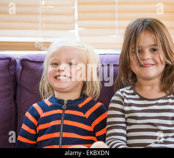 Ritratto di giovane ragazzo e ragazza, seduto sul divano, sorridente Foto Stock