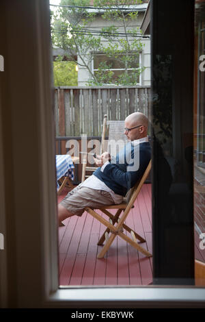 Uomo che utilizza phone sul patio Foto Stock