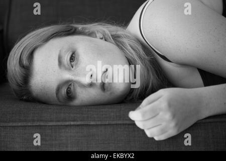 Giovane donna sdraiata sul divano Foto Stock
