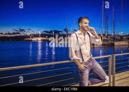 Giovane uomo utilizza lo smartphone dal porto di Cagliari, Sardegna, Italia Foto Stock