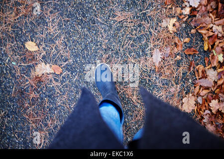 Elevato angolo di visione della donna in stivali di gomma passeggiando in foglie di autunno Foto Stock